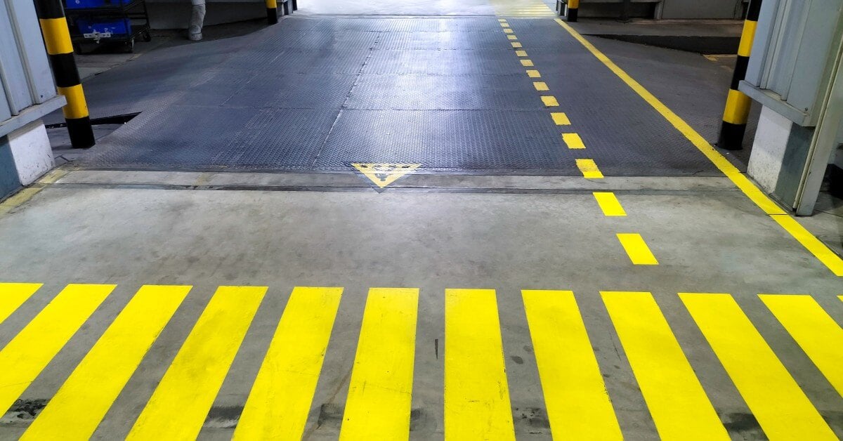 The entrance of a warehouse with yellow striped lines in the foreground and right side for a pedestrian walkway.