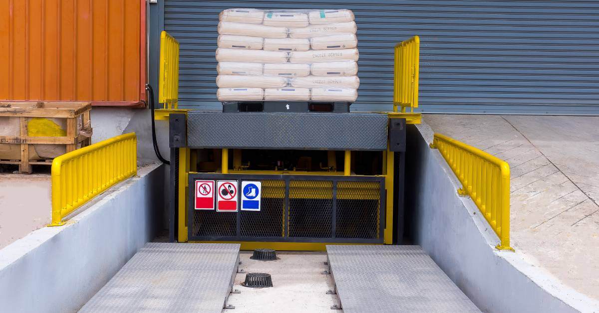 A loading dock leveler ramp installed outside of a warehouse with a big shipment wrapped up and ready for loading.